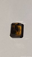 Top view of the natural Madeira citrine gemstone showing emerald cut facets and deep cognac color under natural light.