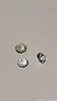 Three round aquamarine gemstones on a white background, showing clear facets and light color variations.