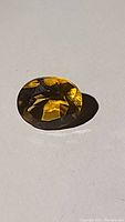 Photo of the oval cut Madeira citrine gemstone showing its whiskey color and faceted cut.