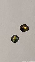 Pair of oval cut multicolored sapphires showing natural color variation and high luster on a light background.