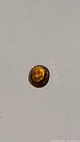 Close-up photo of the oval cut burnt brandy orange Tanzanian zircon gemstone on a plain background.