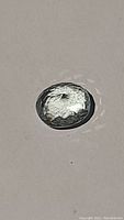 Oval cut aquamarine gemstone with visible inclusions, on white background, showing transparency and light reflection.