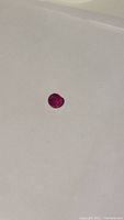 Round cut natural treated ruby gemstone on a white background. Visible bright pink-red color and facets of the cut.