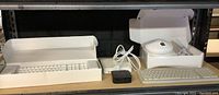 Wide view of Apple keyboard, Apple TV, and Apple AirPort Extreme in original boxes with cables and adapters visible