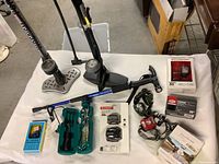 Wide view of table showing two tire pumps, headlamps including boxed Schwinn and Bell products, and a green tool case with cycling tools.