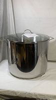 Front three-quarter view of stainless steel stock pot with glass lid on