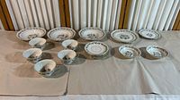 Full display of Royal Jackson Fleur De Blanc china spare pieces on a table including plates and bowls arranged in rows