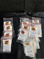 Lot of Unocal Union 76 San Francisco 49ers commemorative MVP pins for sale, displayed on a black surface in clear individual plastic bags with backing cards.
