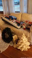 Photo of the Christmas decorations lot showing wreath, ceramic tree, musical Rudolph figurine, votive holders, wrapping paper rolls, and soap dispenser arranged on and next to a loveseat.