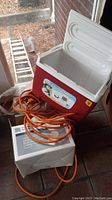 Igloo Island Breeze cooler with orange extension cords coiled beside it