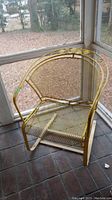 Yellow metal outdoor rocking chair, side angle, showing curved armrest and rocking base.