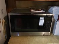 Full front view of microwave oven showing black glass door and stainless steel edges with control panel on right.