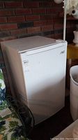 Front and side views of white Arctic King mini freezer on porch showing overall condition and size
