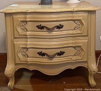Front view of wooden night stand showing two drawers with decorative metal handles and curved legs.