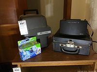Bell and Howell Autoload 346A movie projector with cover, Polaroid 350 camera in case, Fujifilm waterproof disposable camera box