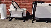 Bassinet and diaper genie side by side outdoors on concrete with brick backdrop