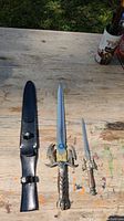 Photo showing large sword, small dagger, and black leather sheath on a wooden surface