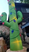 Photo of a 12-foot tall bright green Christmas cactus inflatable decorated with multicolored holiday light designs, illuminated internally.
