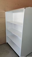 Full side view of the white shelving unit showing three adjustable shelves and the solid side panel.