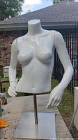 Front view of the white female torso mannequin with arms and adjustable metal stand showing torso details and glossy finish.