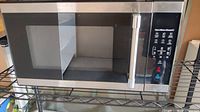Front view of the black Hamilton Beach microwave showing door with see-through window and stainless steel handle.