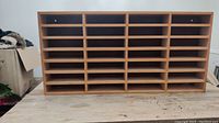 Front view of wooden letter tray organizer with 28 compartments, placed on a table.