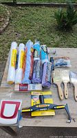 Full lot overview with all rollers, brushes, frames, and accessories laid out on a wooden table outdoors next to grass and bricks.