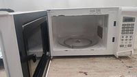 Open microwave showing internal rotating plate and white interior