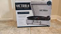Photo of the Victrola Bluetooth turntable retail box showing features like 3-speed turntable, Bluetooth connectivity, 3.5mm aux-in, RCA output, and premium fabric finish.
