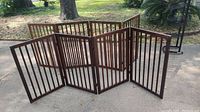 Two wooden 4-panel room dividers arranged in a semi-circle outside on concrete ground in daylight.