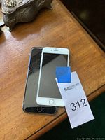 Two iPhones stacked with front screens visible, one white, one black, with signs of wear.