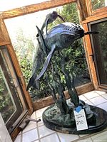 Full view of patinated bronze sculpture showing mother and daughter whales amidst kelp on oval base