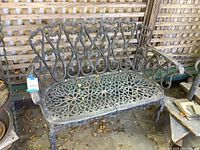 Full view of the heavy metal garden bench with intricate ornate design on seat and back.