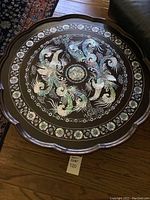 Top view of the round foldable table showing the detailed peacock and bird mother of pearl inlay design and floral border.