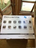 Top and front box view showing product name, key features, power, and product image with steamer hanging a shirt.