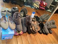 Eight pairs of assorted women's footwear displayed on hardwood floor in front of mirror