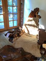 Overall view of burled wood lounge chair with sheepskin draped and matching footstool in room setting