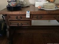 Front view of desk showing top surface, carved drawer fronts and wrought iron handles