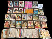 Top view of assorted baseball cards spread in rows showing a mix of players from different teams and years, displaying front and back of cards with varied designs and colors.