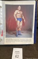 Color photo of Edouard Carpentier, muscular wrestler in blue trunks and boots, standing posed against plain maroon background from 1973 publication.