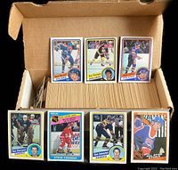 Cardboard box filled with stacked O-Pee-Chee hockey cards. Front row displays Mark Messier, Ray Bourque, Paul Coffey, Tom Barrasso, Steve Yzerman, Dave Andreychuk and Wayne Gretzky cards.