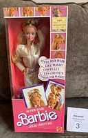 Front view of sealed Super Hair Barbie doll in original pink box showing doll in white outfit with long blonde hair and various photos of hairstyles.