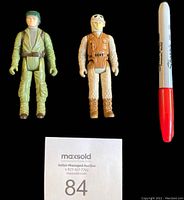 Front view of both Star Wars action figures, the left one is Endor Rebel Soldier in green uniform, the right one is Rebel Soldier Hoth Battle Gear in cream and orange outfit, 3.75 inches tall, Sharpie pen shown for scale