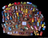 Overhead photo showing full collection of 105 assorted diecast toy vehicles arranged in a circular pattern on a wood floor