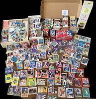 Wide top-down view of boxes and stacks of loose baseball cards spread on a table. Several cards are visible including vintage cards with player photos and team logos.