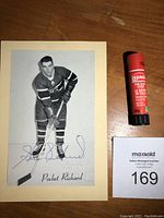Full view of the signed black and white Beehive hockey photo mounted on beige cardstock, showing Henri Richard in uniform, with the blue ink autograph and printed 'Pocket Richard' inscription below.