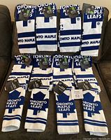 Twelve folded white and blue Toronto Maple Leafs hand towels and facecloths arranged on a couch, all with original tags attached.