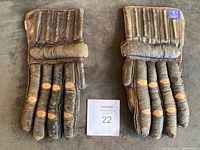 Pair of vintage brown leather hockey gloves laid flat showing padded backs and worn leather.