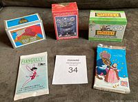 Lot containing three sealed card box sets and two sealed card packs arranged on a dark fabric surface.