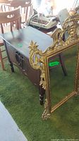 Ornamental framed mirror with gold-tone metal rim, decorative leaf and scroll design.